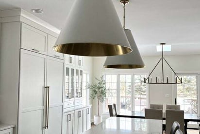 close up shot of kitchen pendant lights with a modern dining room chandelier suspended in the background