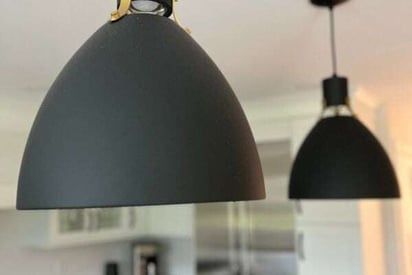 Close up photo of matte black brushed metal pendant lights with curved shades