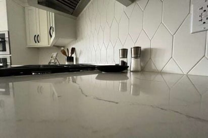 Glossy kitchen counter top showing the reflection of the hexagonal tile backsplash