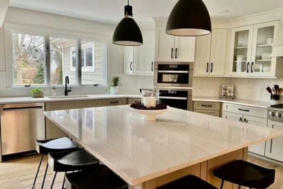 square kitchen island with black bar stool seating and two black pendant lights