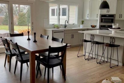 Kitchen dining room table with 6 black plastic chairs surrounding a rectangular table