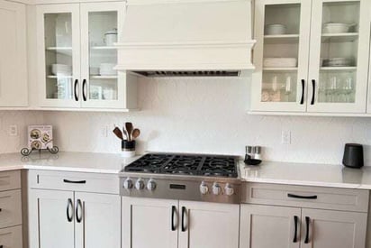 Kitchen stove built into the cabinet for a flush finish. A white exhaust fan is mounted above