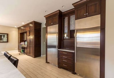 Two stainless steel refrigerators and a small desk with a computer in the kitchen