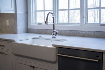 close up of a kitchen sink faucet that has a large single ceramic basin