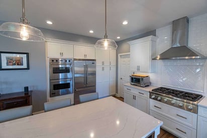 Kitchen three door refrigerator and a double door convection oven built into the white cabinets