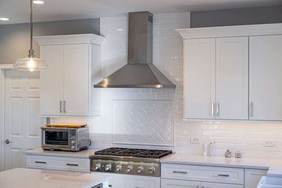 Kitchen over with a large silver exhaust fan mounted above and a table top toaster oven on the left