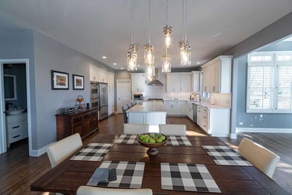 kitchen dining room table with a bowl of fake fruit in the middle and 6 black and white plaid placemats in front of each chair