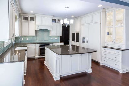 White chandelier hung over a kitchen island to cast lots of cool light around the white space