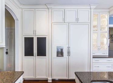 Kitchen fridge built to blend in with the surrounding white kitchen cabinets