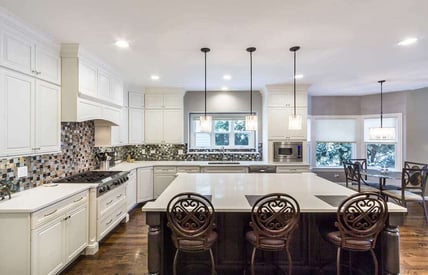 Wide angle of a luxury kitchen remodel that has 3 bar stool chairs at the island for seating