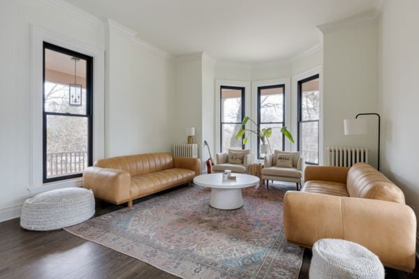 Living Room featuring white walls and black framed windows, a painted radiator, with a large bay window and tan leather and beige apolstry seating