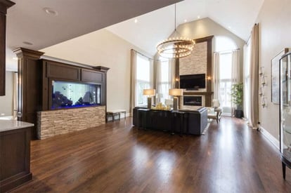 Spacious living room with a couch, wall mounted TV, floor to ceiling windows, and a cathedral ceiling