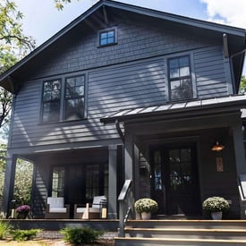 Two story home with black siding and trim with a screened in porch next to the front door