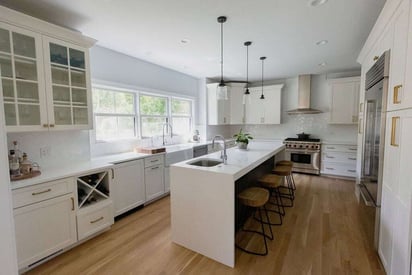 Kitchen with a large island with 3 barstool seats and pendant lights suspended above