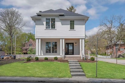 White home exterior that is two stories, a corner lot, with a lush yard out front