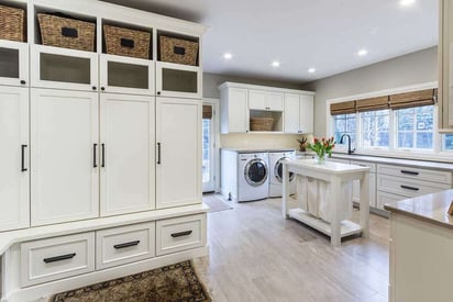 Mudroom and laundry room combination with white lockers and two side-by-side laundry machines that are front load