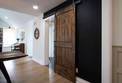 Sliding brown barn door to section off a living room from a bathroom