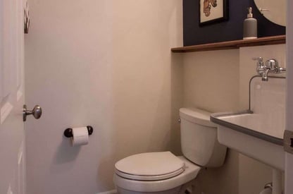 Guest bathroom toilet with a floating shelf above the tank