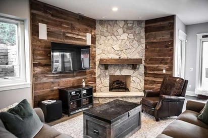 Basement living room with chairs and a sectional couch surrounding a stone hearth