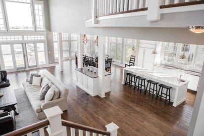 Lake house kitchen island seen from a stair view with black stools