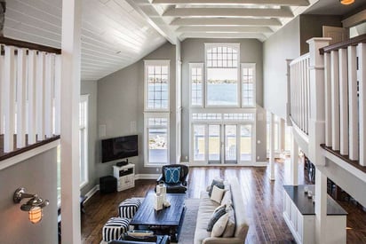 Cathedral ceiling living room with large floor to ceiling windows covering an entire wall