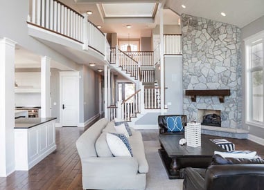 Lake house living room with coastal stone walls and a large center staircase