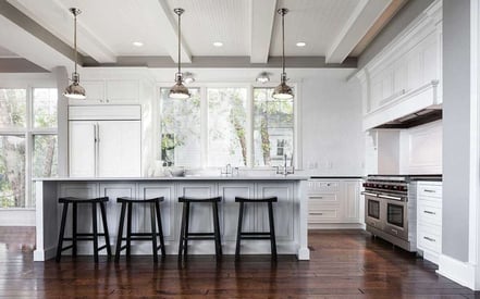 Kitchen island seating area with four black stools and 3 pendant lights strung above the table