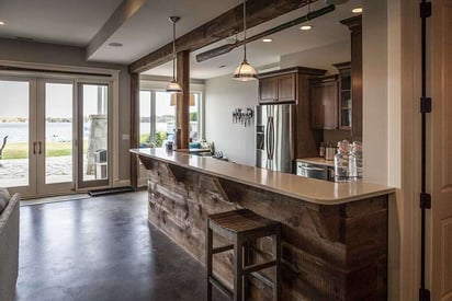 Basement bar with stools for seating and stone floors for a coastal aesthetic