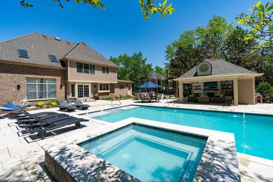 luxury pool home with a detached hot tub closest to the camera and a two story home in the background