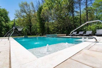 Corner shot of an inground home pool with fountains and a deep end