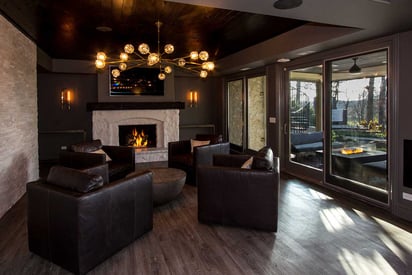 Basement sitting room with a artistic chandelier and a stone hearth fireplace on the wall